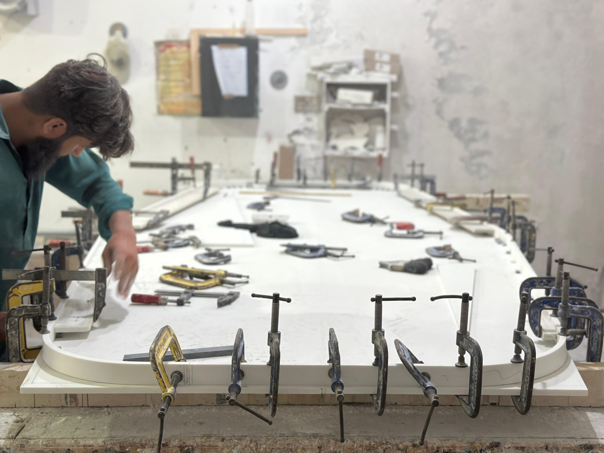 Fabricator hand-finishing a curved Corian countertop clamped on the bench